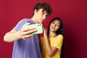 nice guy and girl in colorful T-shirts with a phone red background