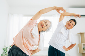 家で運動する高齢者の男女（ラジオ体操）
