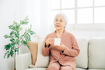 ホットドリンクを飲む高齢者女性
