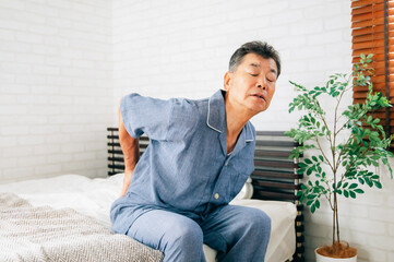 寝室で体調を崩す高齢者男性（腰痛）
