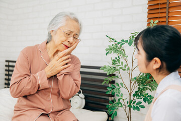 痛がる高齢者女性と介護士の女性（虫歯）