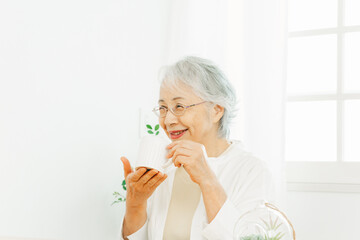 マグカップで飲み物を飲む高齢者女性
