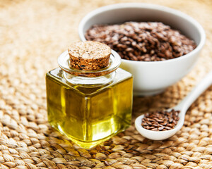 Flax seeds or linseeds in spoon and bowl with glass of linseed oil
