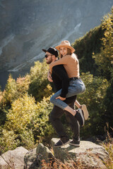 Happy loving couple of tourists walking in mountains enjoying view.