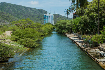 Río Gaira entre edificios de la ciudad y montañas al fondo ubicado cerca del balneareo Rodadero en Santa Marta, Colombia