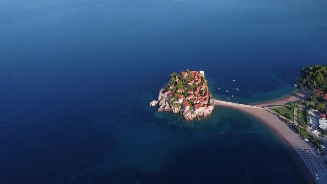 Bird's eye view of coastal zone with beautiful island and bridge. Main tourist location in the region. Drone shot of Sveti Stefan (Saint Stephen) island in Montenegro.