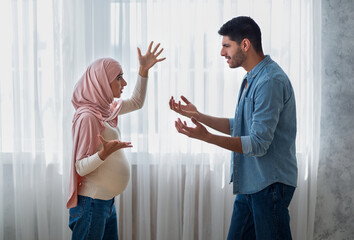 Pregnancy and relationship problems. Pregnant arab woman arguing with husband at home, side view