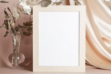 Portrait empty wooden frame mockup, golden branch in vase and textile on beige background, interior, home design. space for text. 