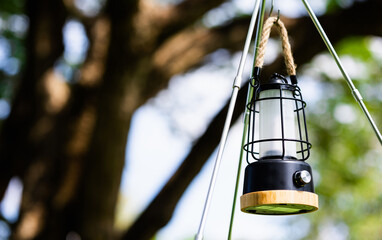 Led camping lamp on the nature big tree and green grass background.
