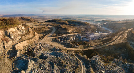 Aerial view of open pit mining site of limestone materials for construction industry with excavators and dump trucks