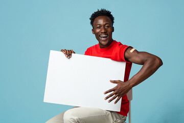 Cheerful Vaccinated Black Guy With Plaster On Arm Holding Blank Placard