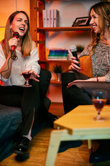 Talented girls with beautiful voices sit at home and sing a duet at karaoke night.