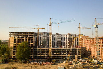 High multi storey residential apartment buildings under construction. Concrete and brick framing of high rise housing. Real estate development in urban area.