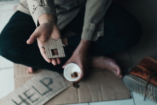  Poor tired depressed hungry homeless man holding a cardboard house. nostalgia and hope concept.
