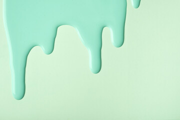 Light green liquid drops of paint color flow down on olive pastel background. Abstract cyan backdrop.