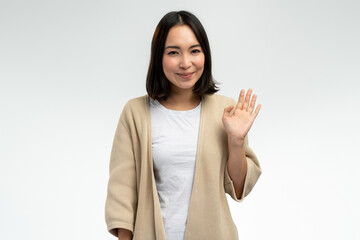 Portrait of charming woman standing, waving hand and saying Hi to camera with smile