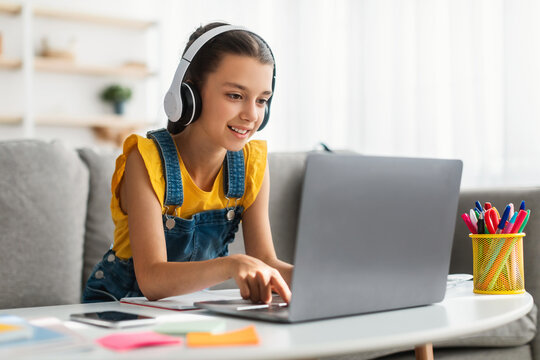 Girl sitting at desk, typing on keyboard, wearing headphones