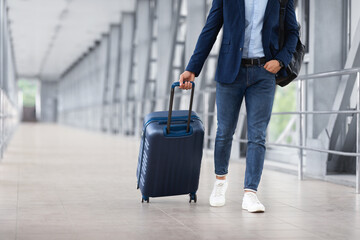Unrecognizable Man In Casual Clothes Walking With Luggage At Airport Terminal
