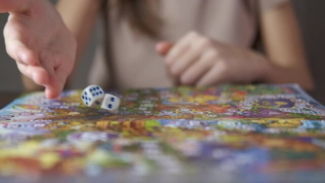 Strategic board game. A view of child hands with a dice by the table with game.