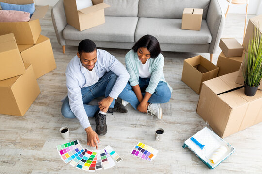 Home renovation concept. Young black couple choosing color palette for painting walls in new house, above view