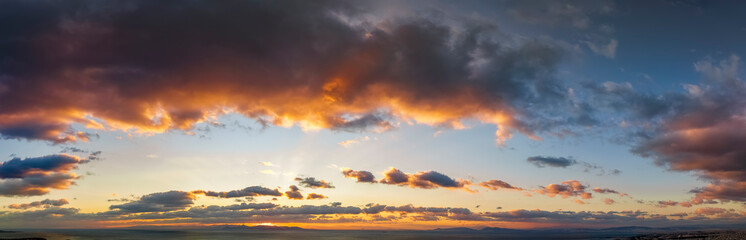 Wide aerial panorama of a cloudy sunset sky over the sea as background or texture