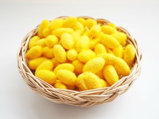 Yellow cocoon in basket on brown wooden background. closeup photo, blurred.