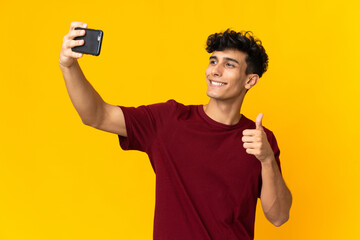 Young Argentinian man isolated on yellow background making a selfie with mobile phone