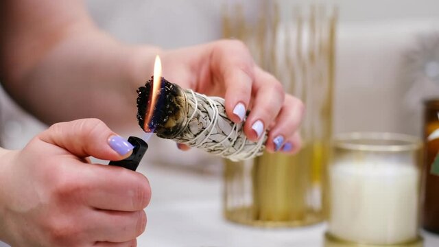 Female hand sets fire to incense on a copper bowl. Aroma therapy, to relax after a hard day. Smells for concentration, purification and clarification of consciousness.