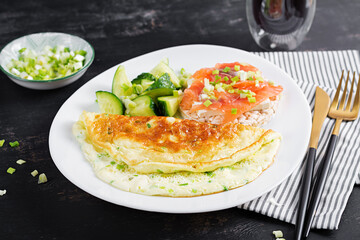 Breakfast. Omelette with green onions and sandwich with salmon on white plate.  Frittata - italian omelet.