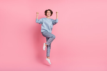 Full body photo of cool millennial lady jump hands fists wear jumper jeans shoes isolated on pink background