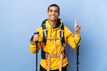 African American man with backpack and trekking poles over isolated background pointing up a great idea