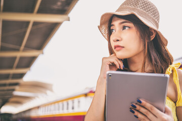 portrait asian girl looking for travel information by tablet traveler by the train.