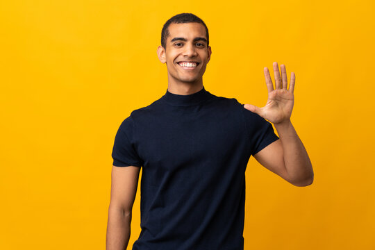 African American man counting numbres over isolated yellow background