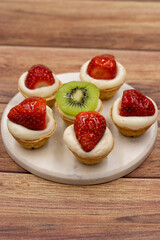 Delicious tiny tartlets (tarts, open pastry pies) on a wooden background. close up