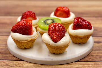 Delicious tiny tartlets (tarts, open pastry pies) on a wooden background. close up