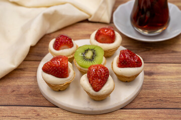 Delicious tiny tartlets (tarts, open pastry pies) on a wooden background. close up