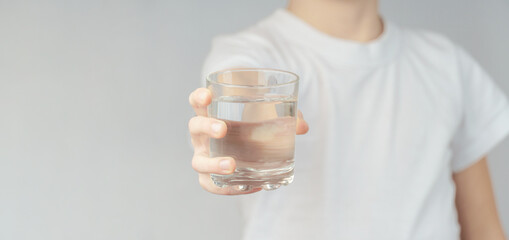 young man holding a glass of water, close-up