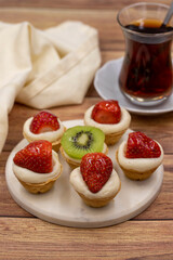 Delicious tiny tartlets (tarts, open pastry pies) on a wooden background. close up