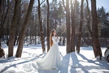 blonde with long hair, a girl in a long white dress walks in the winter forest, the snow queen, the bride with a bouquet of dianthus