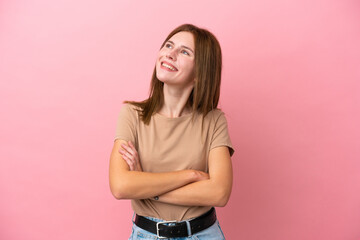 Young English woman isolated on pink background looking up while smiling