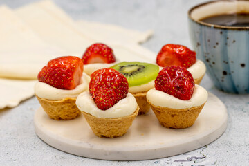 Delicious tiny tartlets (tarts, open pastry pies) on a stone background. close up