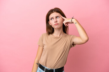 Fototapeta premium Young English woman isolated on pink background making the gesture of madness putting finger on the head