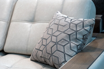 beige pillow with a zigzag pattern lies in the corner on a blue comfortable sofa in the living room