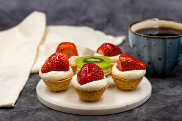 Delicious tiny tartlets (tarts, open pastry pies) on a dark background. close up