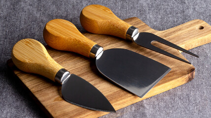 Cheese cutter set with wooden handles. Group of cheese knives on the cutting board.Top view