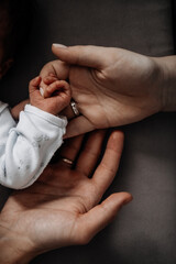 Parents hold the hand of a newborn baby, trust and care