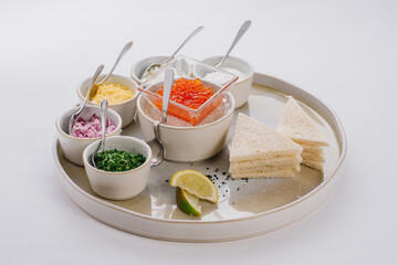 Dish with red caviar and herbs on white background