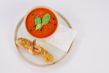 Tomato soup with tiger prawns on a white background