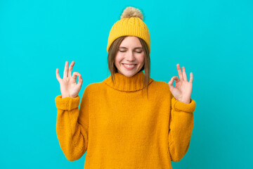 Young English woman wearing winter jacket isolated on blue background in zen pose