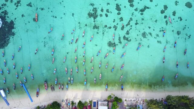 Aerial view of stunning summer landscape. A group of fishing long tail boat in turquoise Andaman sea and white sand beach at Koh Lipe or Lipe island, Satun, Southern Thailand. 4K drone video